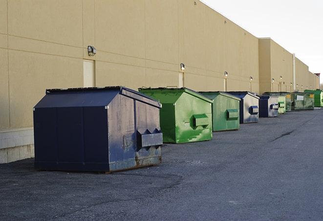 a pile of demolition waste sits beside a dumpster in a parking lot in Hastings